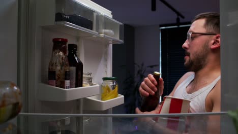 hombre comiendo un bocadillo nocturno del refrigerador
