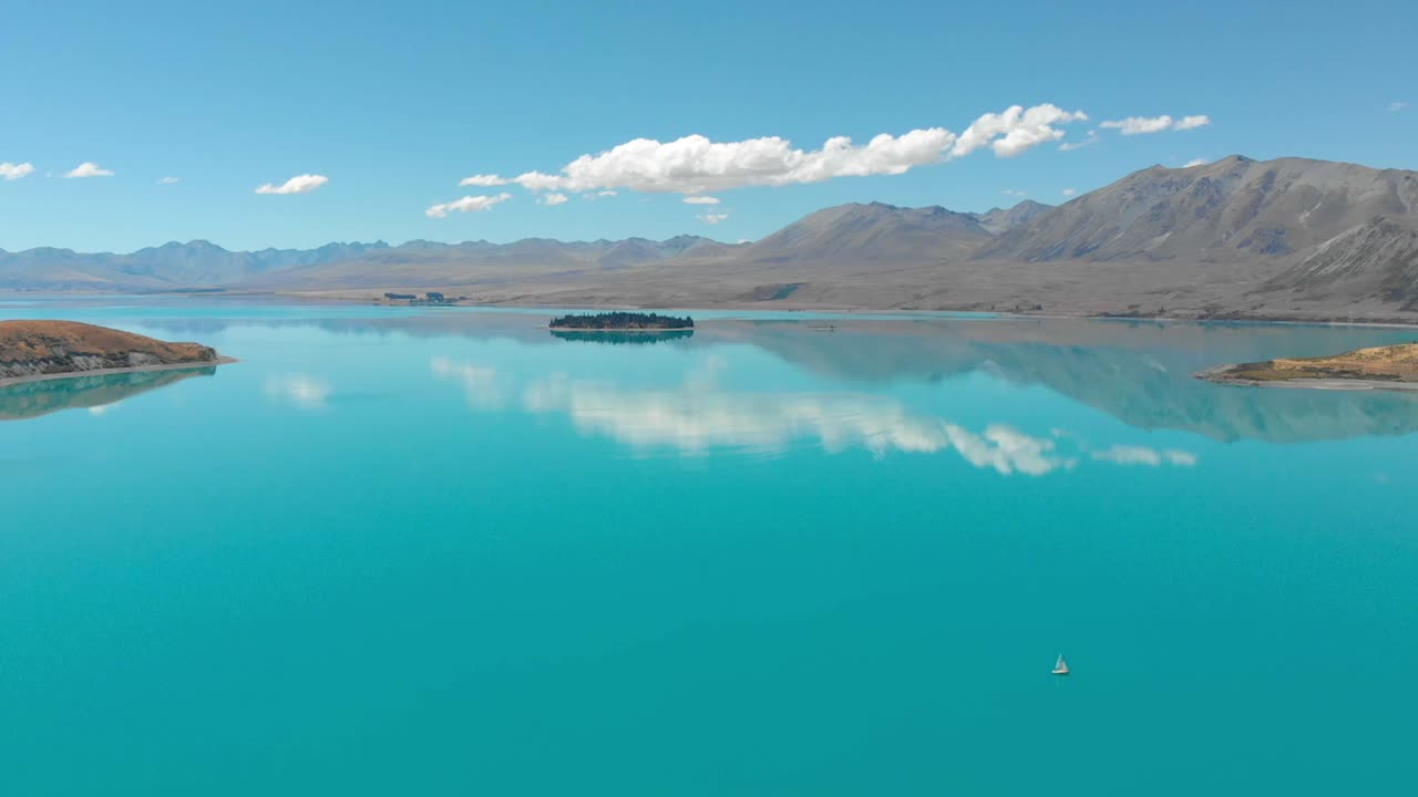 вид с воздуха на озеро текапо, новая зеландия, с панорамированием камеры над озером в солнечный день