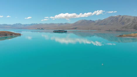 Vista-Aérea-Del-Lago-Tekapo,-Nueva-Zelanda,-Con-Una-Cámara-Panorámica-Sobre-El-Lago-Durante-Un-Día-Soleado