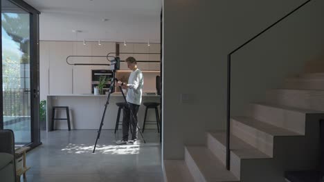 close up of floor planner walks slowly holding tripod with matterport device mounted through modern home finding a new spot to place the device for the next scan