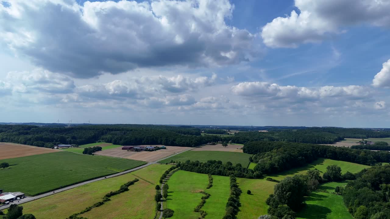 Peaceful and beautiful rural landscape with farm fields in summer. drone wide shot of American countryside. Cultivated fields and greened mountains with puffy clouds at summer sky. Panorama cozy vibes