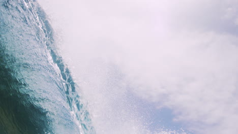 Low-angle-view-of-sunlight-glistening-across-clear-wave-barreling-into-vortex-underwater