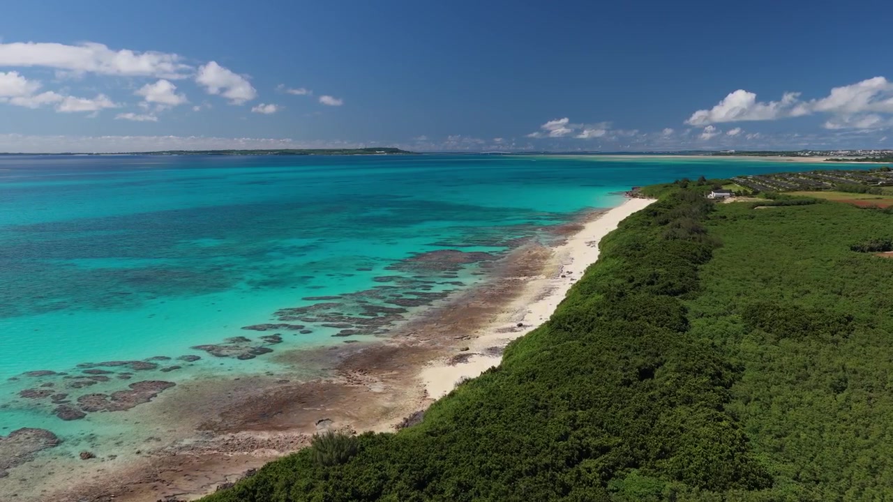 Riprese aeree orizzontali che avanzano sopra la costa di sabbia bianca e le acque turchesi della spiaggia di Musunun sull'isola di Kurima, Miyakojima, Okinawa, Giappone.
