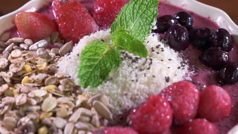 Tazón-De-Batido-Con-Fresas,-Avena,-Granos-Y-Arándanos-En-Un-Tazón-Blanco-De-Cerca-Girando-Sobre-La-Mesa