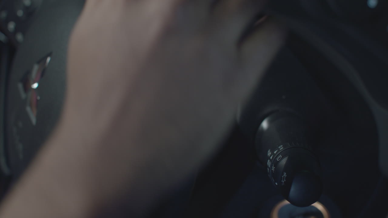 la mano de un hombre de piel oscura pone la llave en el encendido del automóvil y enciende y apaga el indicador o la luz intermitente en el primer plano de su automóvil
