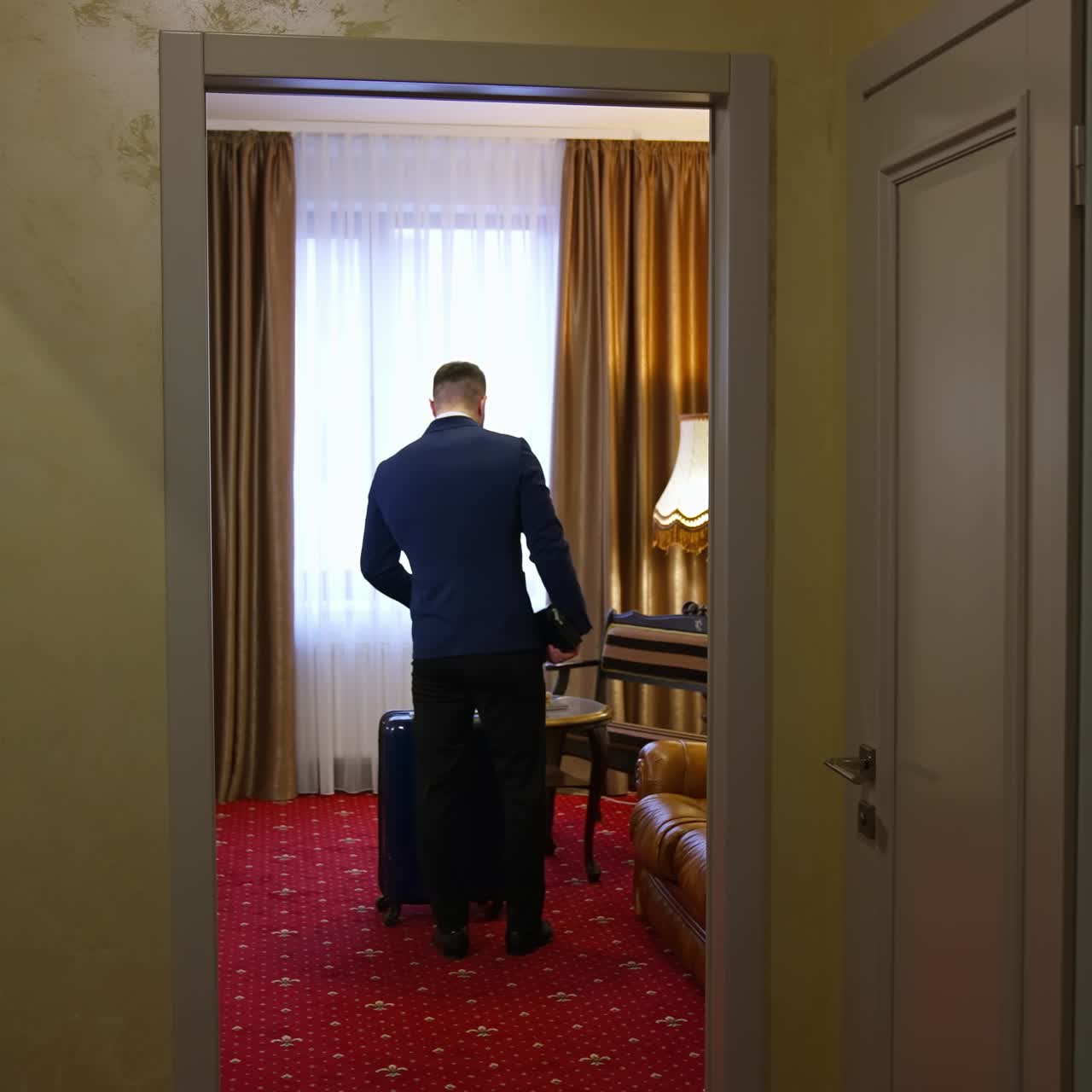 Handsome man walking in a hotel room after business meeting. Businessman enters apartment in luxury hotel