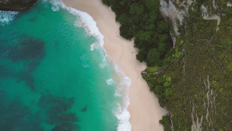 Vista-Superior-De-Las-Olas-De-Agua-Turquesa-Rompiendo-La-Arena-Blanca-De-La-Playa-Kelingking-Conocida-También-Como-Cap-De-T-rex---Nusa-Penida,-Indonesia