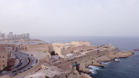 Vista-Aérea-De-Movimiento-De-Vuelo-Hacia-Adelante-Del-Fuerte-Y-El-Castillo-Y-Mar-Abierto-Con-Drones-En-Valletta-Malta