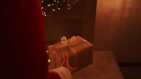 Santa-brings-a-gift-to-children-on-Christmas-night-and-puts-it-near-the-Christmas-tree-in-the-children-house.-the-camera-monitors-the-delivery-of-the-gift-under-the-tree.-High-quality-4k-footage