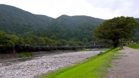 Tourist-walk-through-Shirakawago-Kanazawa-Bridge-in-sideview,-Nagoya,-Japan