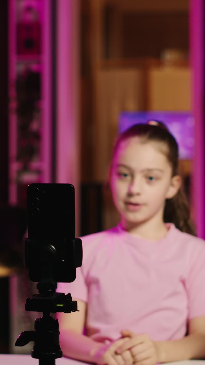 Video verticale. Messa a fuoco su telefono collegato a un treppiede utilizzato per la registrazione di un vlog di famiglia con bambino felice
