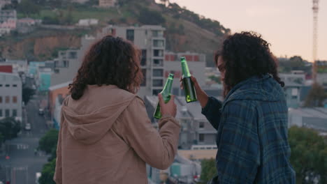 happy friends chatting on rooftop enjoying friendship reunion hanging out drinking refreshing beer sharing view of city skyline at sunset