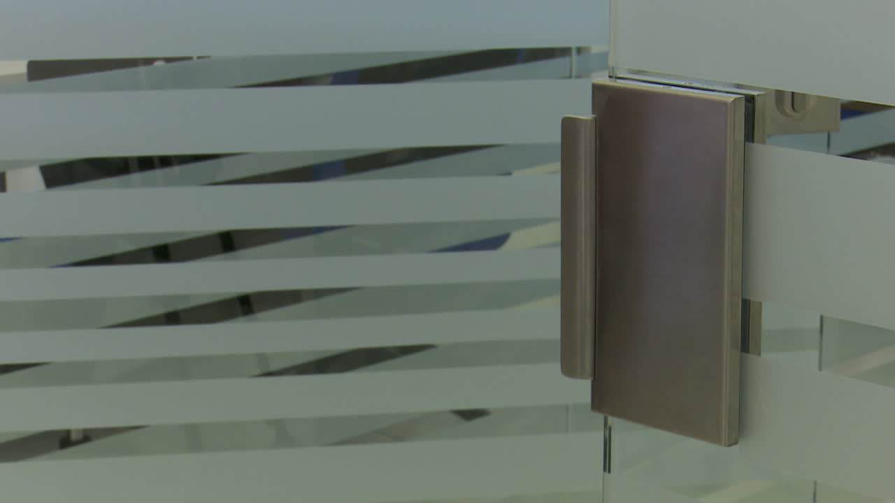 Person opening a glass door with a modern handle.