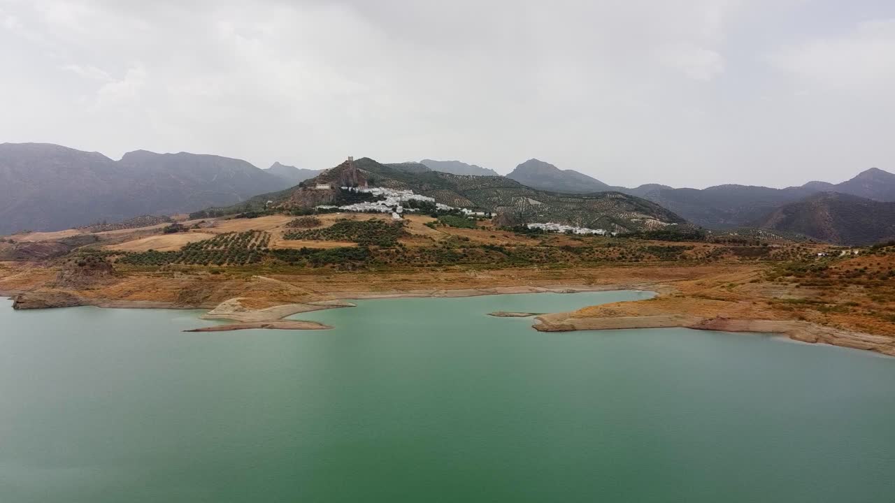 suave escena lateral aérea lago azulado y un castillo medieval en la cima de una montaña