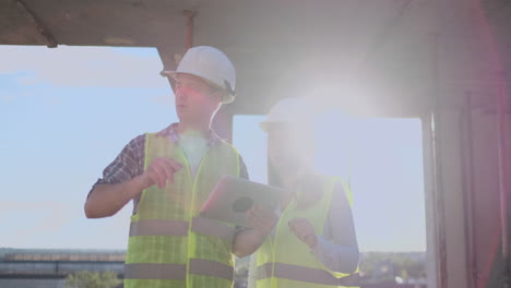 supervisor de un edificio en construcción hombre discutiendo con ingeniero diseñador mujer el progreso de la construcción y examina un plan de construcción.