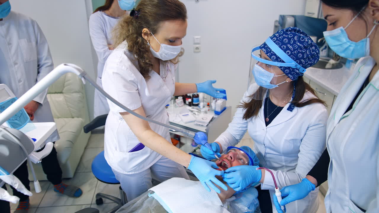 Dentistry teacher talking to the student sitting near the patient. Practical lessons for future orthodontists. Top view.