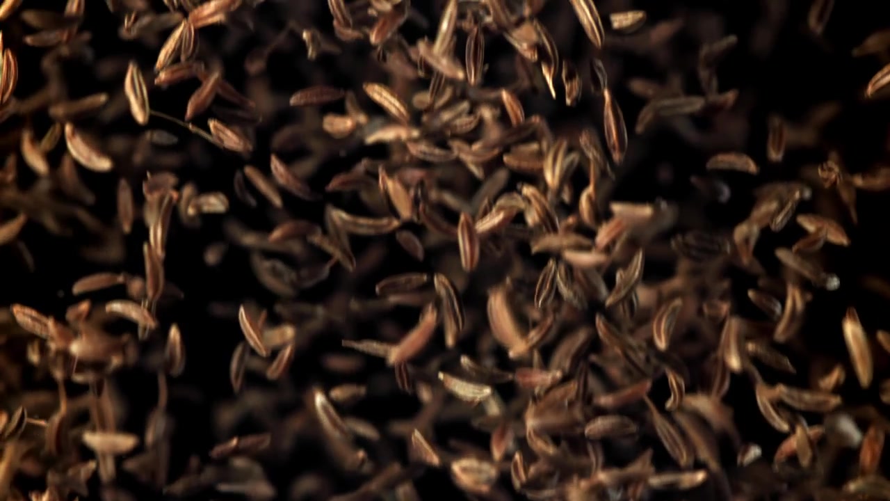 Brown Cumin Seeds Falling in Slow Motion on Black Background