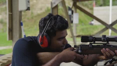 man practicing at the outdoor firing range wearing headphones