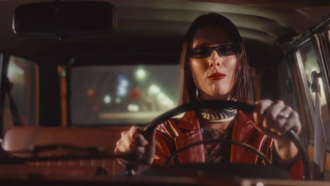 woman in sunglasses singing loudly as driving classic car at night