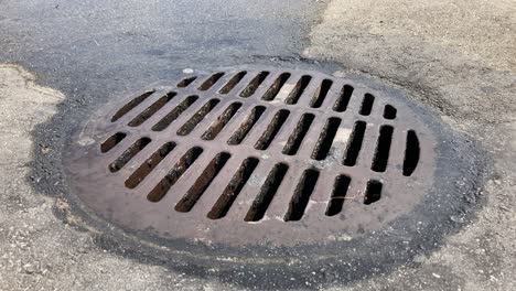 water runs into a manhole cover storm drain on a city street