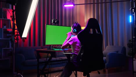 vista trasera de una chica asiática que usa una computadora personal de pantalla verde. bostezando y durmiendo, escritorio iluminado por luz de franja de led rgb