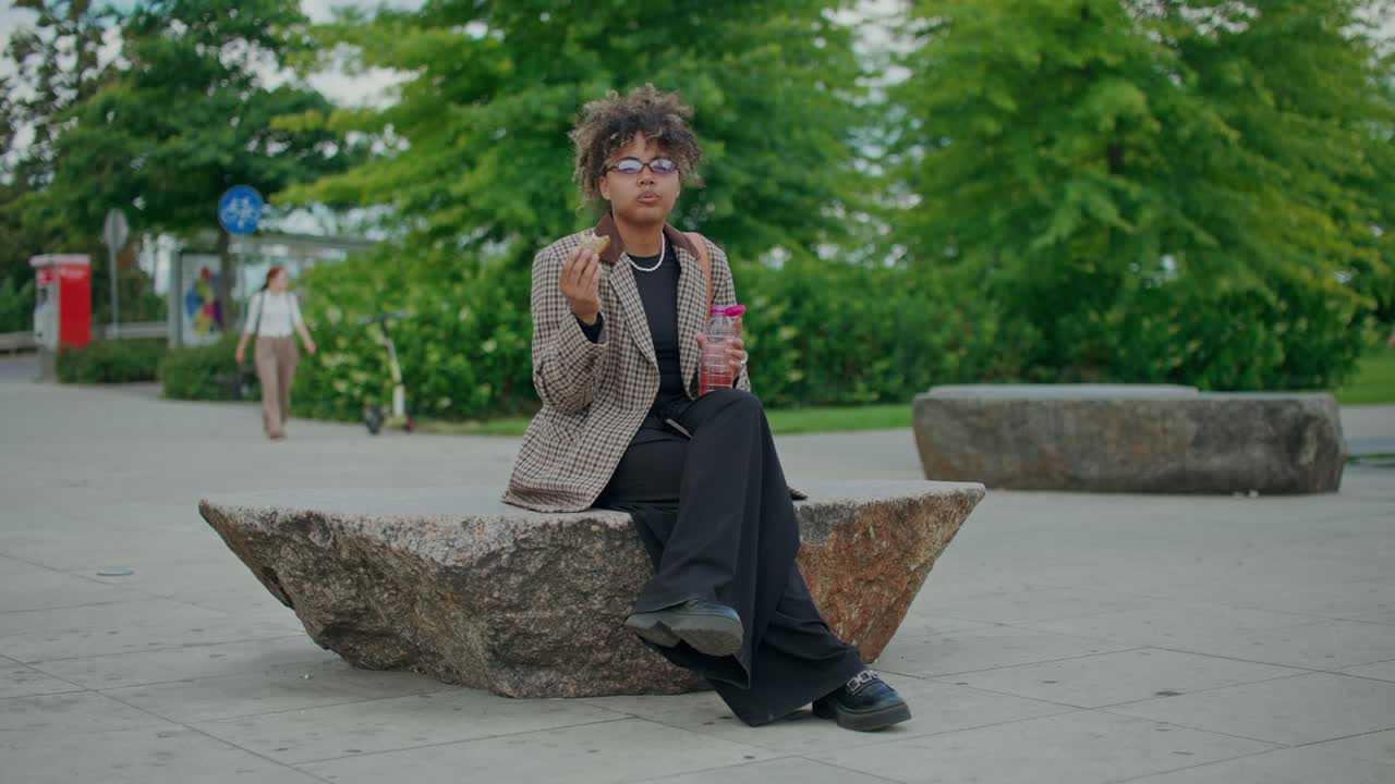 Woman eating lunch and drinking in the park