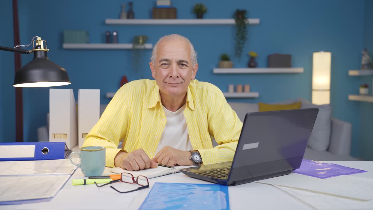 Home office worker old man looking emotional at camera.