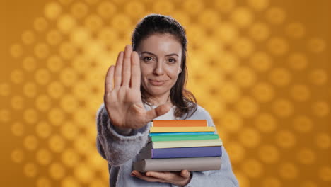 retrato de una mujer severa sosteniendo una pila de libros haciendo una señal de parada gestando