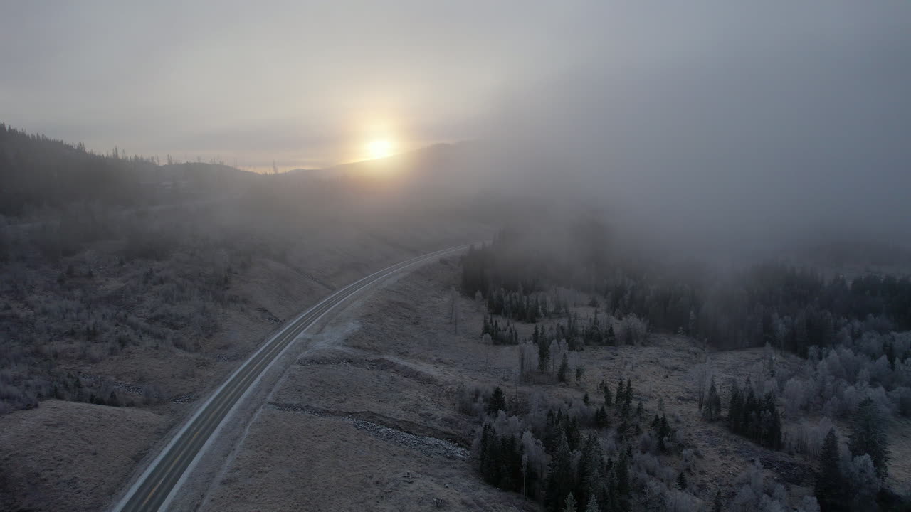 Sunrise over a foggy winter road in the mountains
