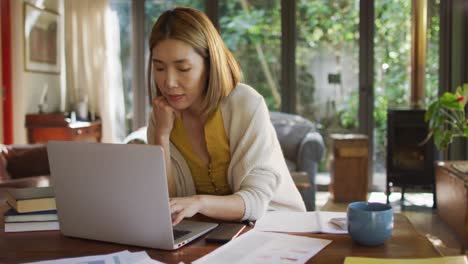 Mujer-Asiática-Sentada-En-La-Mesa-Trabajando-Desde-Casa-Y-Usando-Una-Computadora-Portátil