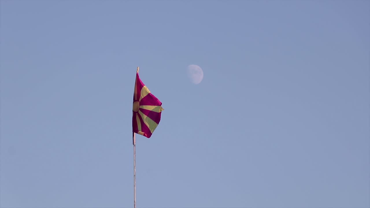 bandera macedonia ondeando en el viento con la luna en la espalda en un cielo azul claro