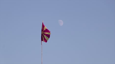 macedonian flag waving on the wind with the moon in the back on a clear blue sky