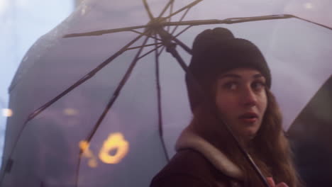 female holding umbrella, walking past cafe, looking through glass window on cold overcast day, wearing black knit cap, brown shearling jacket, with rainy atmosphere outside and wet street
