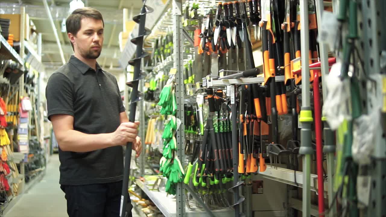hombre comprando herramientas de jardín en una ferretería