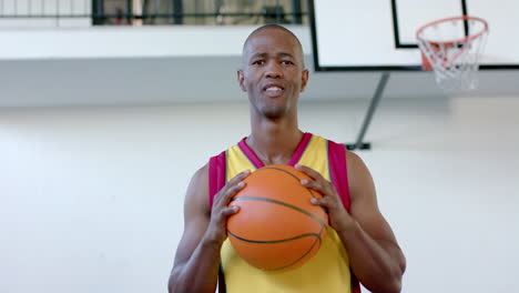 african american man holds a basketball in a gym