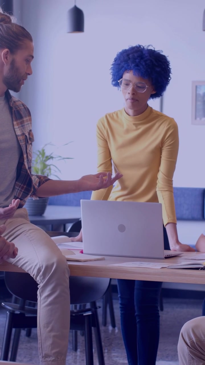 Video verticale: Donna che si appoggia al laptop, uomo che indica e parla, causando notifiche social che oscurano il laptop.