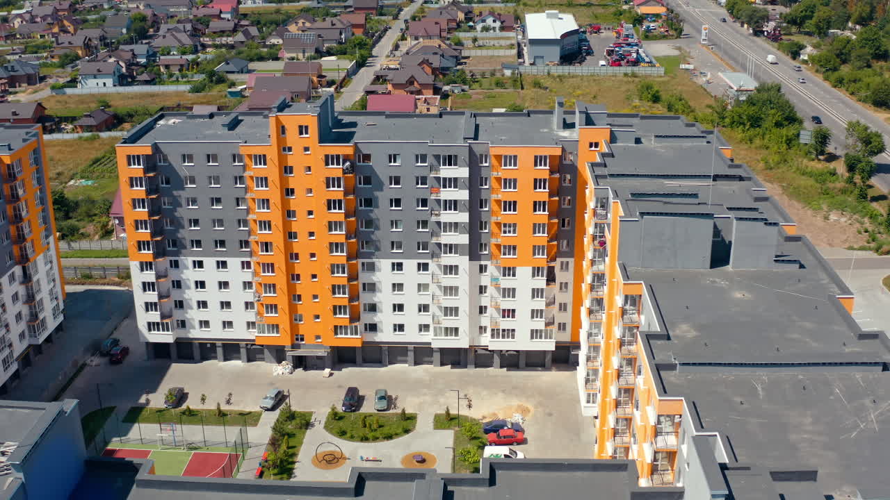 Samtida bostadshus i staden. Drönarvy som flyger nära moderna höga lägenhetsbyggnader med färgglad vägg, belägna i ett nytt stadsområde.