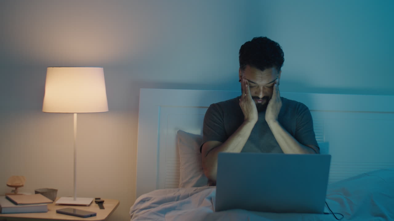 Man Working on Laptop Late in Dark Bedroom
