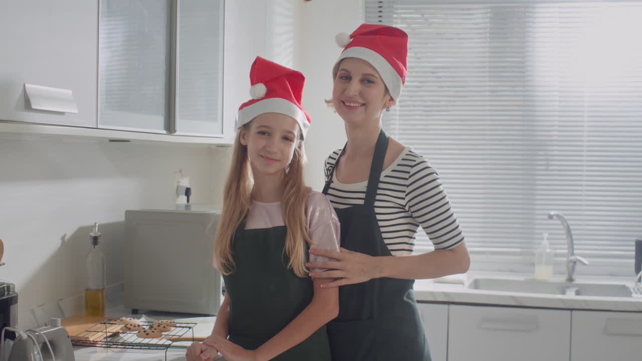 Portrait of Mother and Daughter in Christmas Hats Cooking at Kitchen