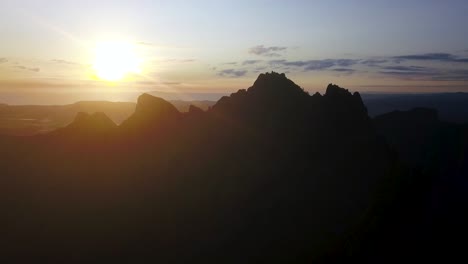 at dusk, a golden sunset and purple clouds set behind craggy mountain peaks in new zealand