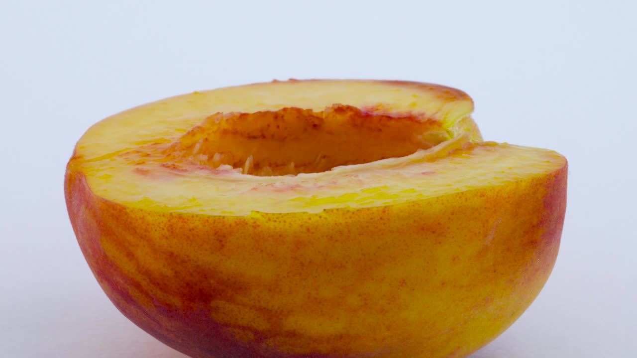 One half of peach fruits without a pit. Rotating on the turntable. Isolated on the white background. Close up. Macro.