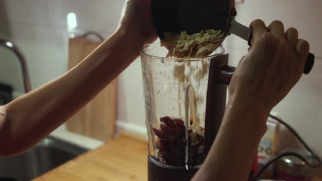 woman puts fried almond into blender