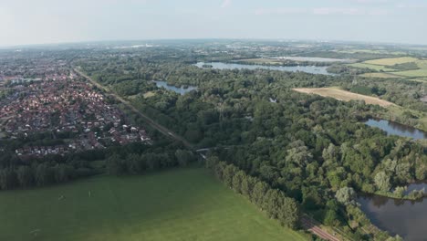 Profile-follow-drone-shot-of-National-rail-train-passing-through-British-countryside-village