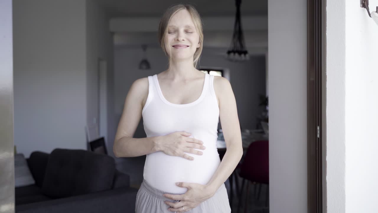 Front view of happy mother touching belly and talking with child