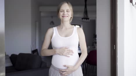 front view of happy mother touching belly and talking with child