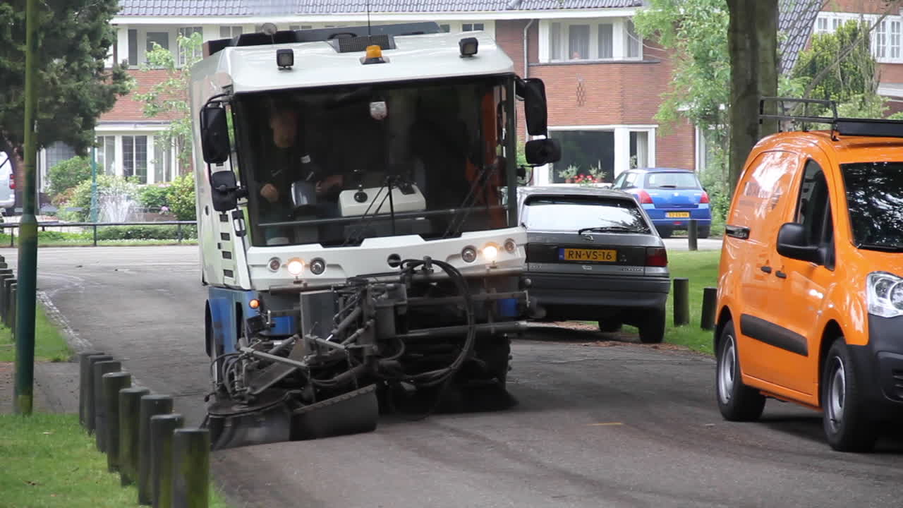 Street sweeper cleaning road near parked cars
