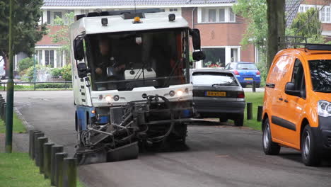 street sweeper cleaning road near parked cars