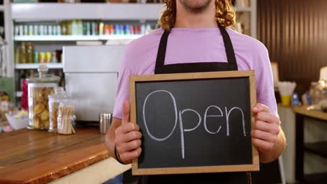 camarero sosteniendo una pizarra con un cartel abierto