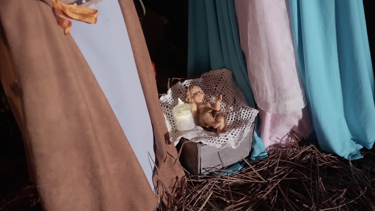 baby jesus figurine lying in manger beside candle in nativity setup