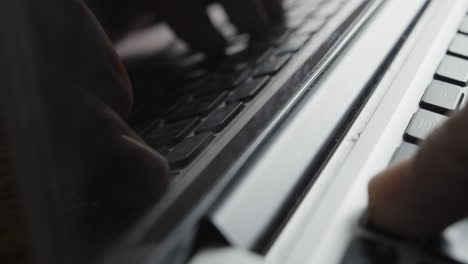 laptop screen reflecting image of fingers typing on keyboard